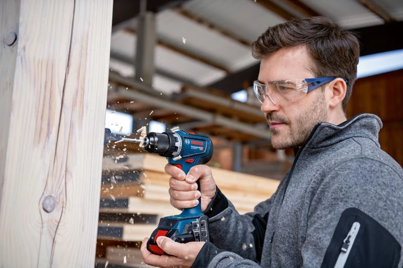Perçage d’une poutre en bois avec une perceuse-visseuse Bosch GSR 18V-90 C Professional.