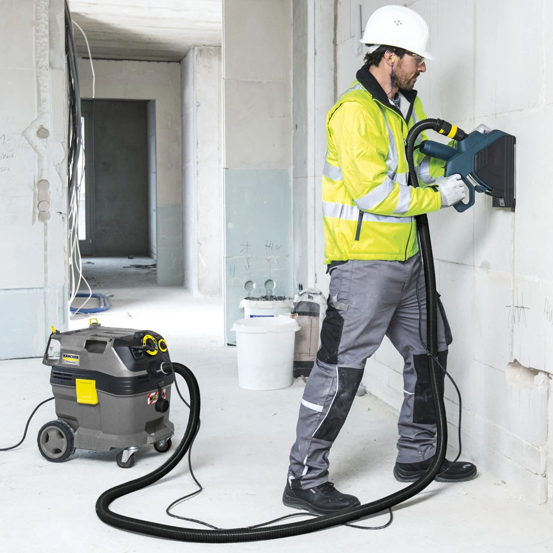 Aspiration des poussières avec un aspirateur Kärcher NT Tact pendant des travaux sur un mur intérieur.